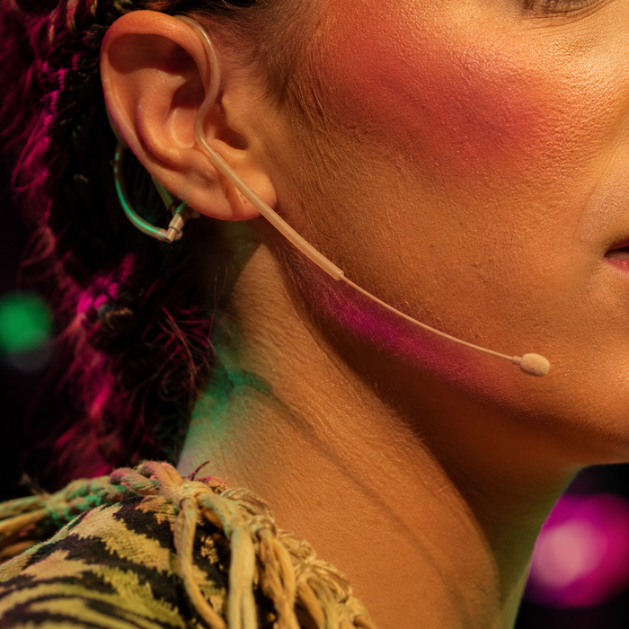A beige Bodymics earset worn by a performer in stage makeup