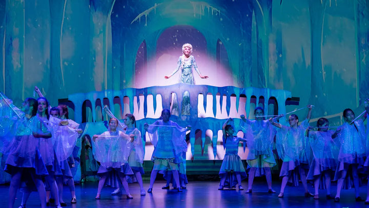A large youth ensemble on stage under blue light